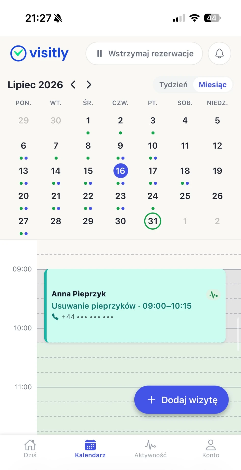 Widok miesiąca w aplikacji Visitly: siatka dni z kropkami wolnych terminów i wizyt